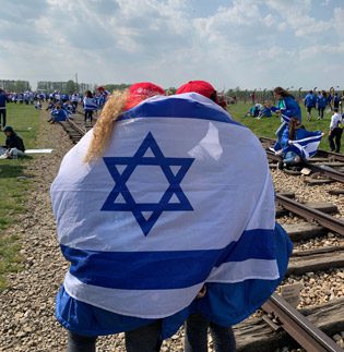 Teens at Auschwitz with Israeli Flag Draped Around
