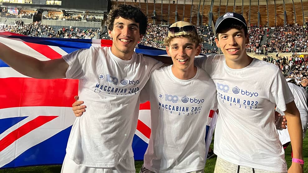 Three teens, boys, draped in flag at Maccabiah Games